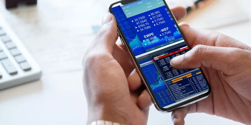 Person nutzt das Smartphone, um den Markt zu verfolgen