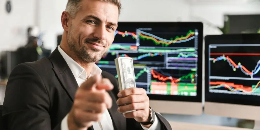 Lächelnder Trader vor Monitoren mit Marktcharts